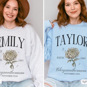 Peut inclure: Deux sweat-shirts avec des noms et des dates de naissance diff&eacute;rents imprim&eacute;s dessus. Le sweat-shirt de gauche est gris cendr&eacute; avec le nom "EMILY" et la date "ESTD. 1997". Le sweat-shirt de droite est bleu clair avec le nom "TAYLOR" et la date "ESTD. 1995". Les deux sweat-shirts pr&eacute;sentent un motif de chrysanth&egrave;me et le texte "Chrysanthemum" avec le mois et le jour de la date de naissance.