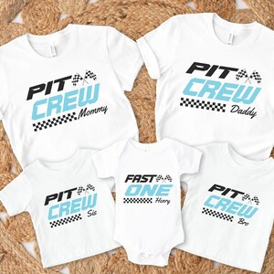 Peut inclure: T-shirts blancs et un body avec des graphiques sur le thème de la course automobile. Les chemises indiquent "PIT CREW" en noir et bleu clair, avec "Mommy", "Daddy", "Sis" et "Bro" en dessous. Le body indique "FAST ONE" avec "Henry" en dessous.