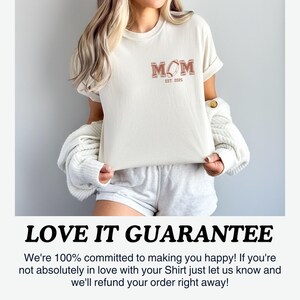 May include: A white t-shirt with a brown graphic that says "MOM EST. 2025" with a football design. The text "LOVE IT GUARANTEE" is below the image. The text says "We're 100% committed to making you happy! If you're not absolutely in love with your Shirt just let us know and we'll refund your order right away!"