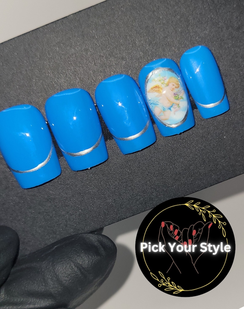 May include: Set of blue press-on nails with silver accents. One nail features a round oval design with a cherub image.