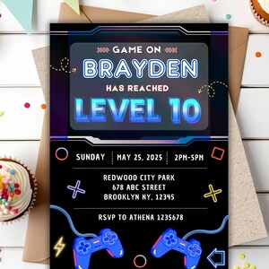 May include: A rectangular birthday invitation card with a black background featuring neon-style graphics of two blue game controllers, geometric shapes, and the text: GAME ON BRAYDEN HAS REACHED LEVEL 10, SUNDAY MAY 25, 2025, 2PM-5PM, REDWOOD CITY PARK.