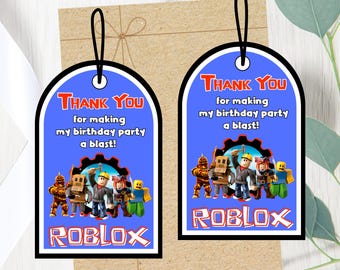 May include: Two blue Roblox-themed gift tags with black borders and a string for hanging. The tags read "THANK YOU" and "for making my birthday party a blast!" with Roblox characters and logo.