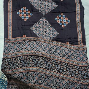 May include: A dark charcoal fabric featuring a repeating pattern of diamond shapes filled with intricate geometric and floral motifs in shades of blue, red, and white. The lower section displays a wide border with dense botanical and geometric designs.