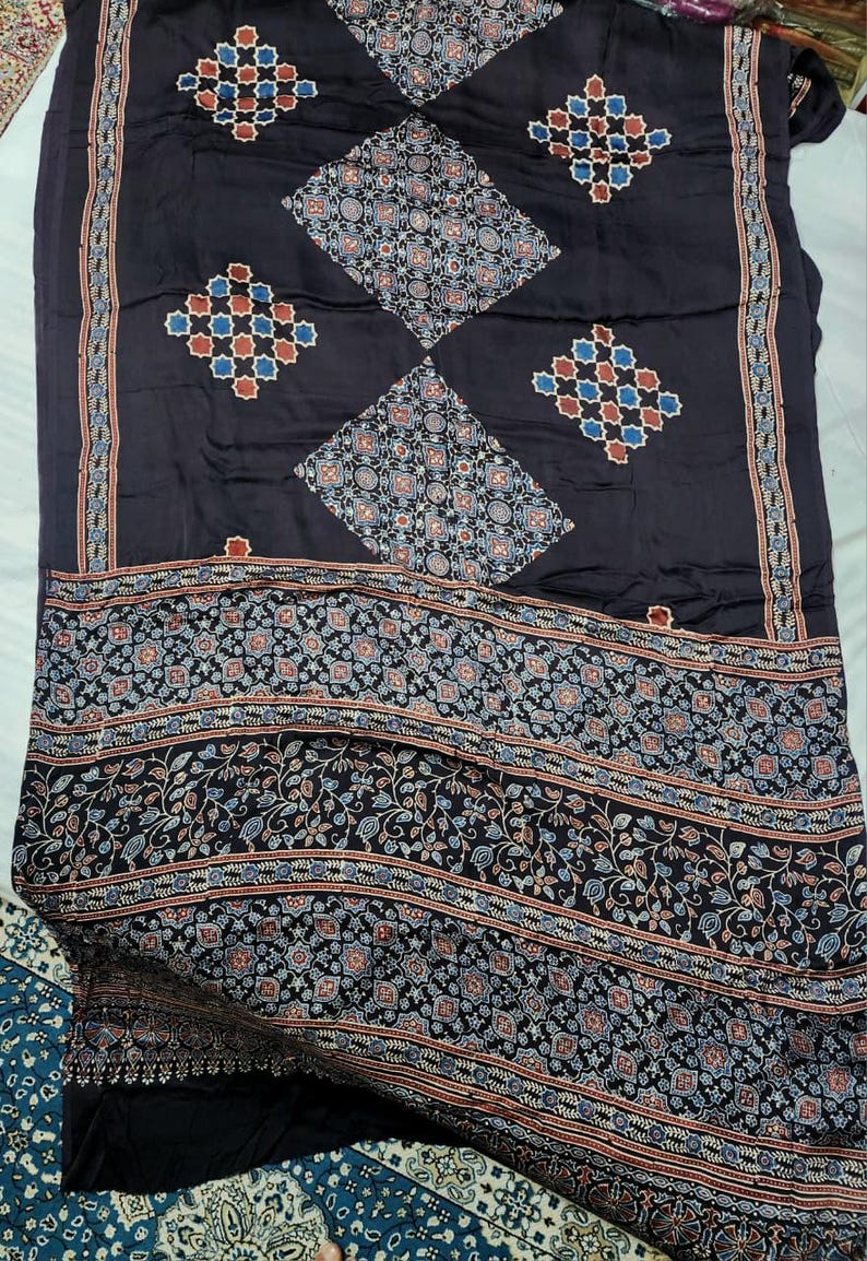 May include: A dark charcoal fabric featuring a repeating pattern of diamond shapes filled with intricate geometric and floral motifs in shades of blue, red, and white. The lower section displays a wide border with dense botanical and geometric designs.