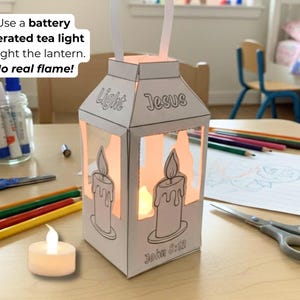 May include: A white paper lantern with the words "Light" and "Jesus" printed on it. The lantern has a candle design and the text "John 3:12". A battery-operated tea light illuminates the inside. Scissors, pencils, and glue are nearby.