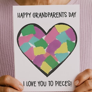 May include: A white greeting card with the text "HAPPY GRANDPARENTS DAY" and "I LOVE YOU TO PIECES!". The card features a black outlined heart filled with colorful paper pieces in shades of pink, green, yellow, and purple.