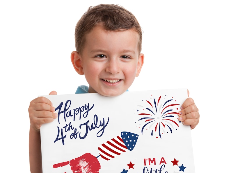 May include: A young boy holds a sign that says "Happy 4th of July" with a red, white and blue firework graphic. The sign also has a red handprint and a firework graphic with the text "I'm a little firecracker".