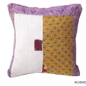Könnte beinhalten: Ein quadratisches Patchwork-Kissen mit weißem Hintergrund und bunten Stoffquadraten. Die Stoffquadrate sind in Violett-, Orange-, Gelb- und Brauntönen gehalten. Das Kissen hat eine gesteppte Textur und ein schlichtes, elegantes Design.