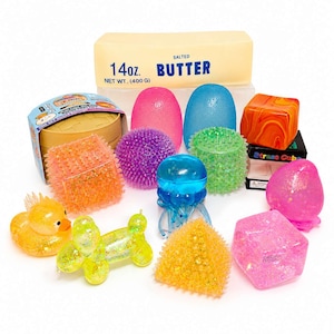 Könnte beinhalten: Eine Sammlung sensorischer Fidget-Spielzeuge, darunter eine gelbe Ente, ein gelber Ballonhund, eine blaue Qualle, ein violetter Stachelball, ein grüner Stachelzylinder, ein orangefarbener Stachelwürfel, ein rosa Ei, ein blaues Ei, ein rosa Klumpen und Butter.