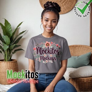 May include: A gray t-shirt with the text "Mockitos Mockups" surrounded by a floral design. The shirt is being worn by a person. The image also includes a green checkmark logo and the text "Genuine Mockups".