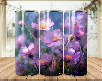 Op de afbeelding: Drie roestvrijstalen bekers met een ontwerp van roze kosmosbloemen met waterdruppels op de bloemblaadjes. De achtergrond is zachtblauw met een wazig effect.