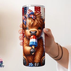 May include: A tumbler featuring a cartoon Highland cow with a red, white, and blue bow and a popsicle. The tumbler has a patriotic design with red and white stripes and blue accents. The cow is brown and fluffy.