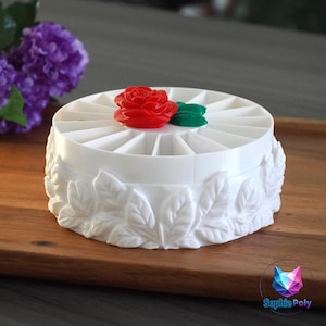 May include: A white ceramic mug with a black handle and the text "But First, Coffee" in a bold, black font. The mug is set against a blurred background, suggesting a cosy setting.