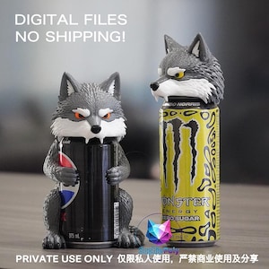 May include: Two gray wolf-shaped can holders. One wolf figure holds a black 375 ml soda can, while the other wolf figure is placed atop a yellow Monster Energy Zero Sugar can. The wolf figures feature white fur accents, pointed ears, and orange eyes.