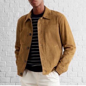 May include: A brown suede jacket with a button-up front and a collar. The jacket has a patch pocket on the left side and a flap pocket on the right side.