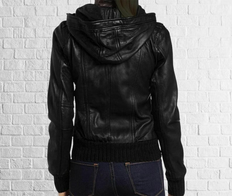 Puede incluir: Chaqueta de cuero negra con capucha, pu&ntilde;os y dobladillo acanalados. La chaqueta tiene cierre de cremallera y un dise&ntilde;o cl&aacute;sico. La chaqueta se muestra desde atr&aacute;s.