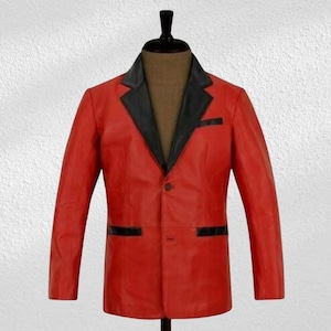 Puede incluir: Un blazer de cuero rojo con solapas y detalles de bolsillo negros. La chaqueta de un solo pecho se exhibe en un maniquí, mostrando su ajuste a medida y diseño clásico. El blazer tiene un cierre de un solo botón y mangas largas.
