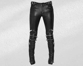 Può includere: Pantaloni in pelle nera con cerniere argentate e fibbia. I pantaloni hanno una vestibilità slim con dettagli a coste sulle ginocchia e cerniere alle caviglie. I pantaloni sono realizzati in pelle liscia e lucida.