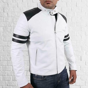 May include: White leather jacket with black shoulder and sleeve detailing. The jacket has a stand-up collar, a full-length zip, and black stripes on the upper arm. The jacket is worn with blue jeans.