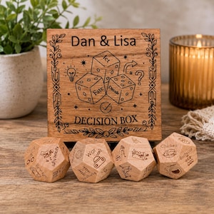 May include: A square wooden decision box with the engraved text Dan & Lisa, three dice illustrations, and the words let, fate, and decide. Four wooden dodecahedron dice are placed in front, each featuring various engraved activity icons and labels.