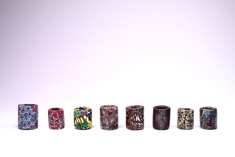 May include: Eight colorful cylindrical beads with intricate patterns. The beads are made of polymer clay and have a variety of colors, including red, blue, green, yellow, and brown.