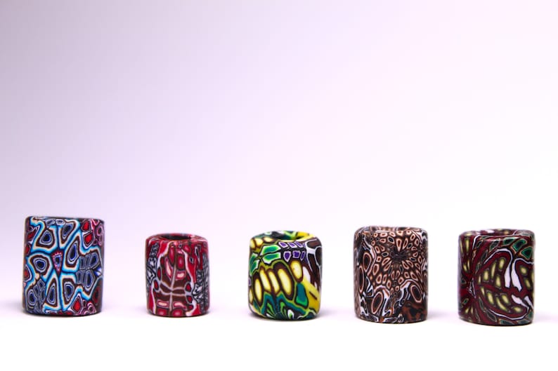 May include: Five colorful cylindrical beads with intricate patterns. The beads are made of polymer clay and feature a variety of colors, including red, blue, green, yellow, and brown.
