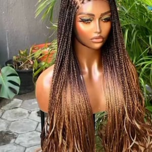 May include: A long, brown and blonde ombre braided wig with a lace front. The wig is styled in a straight, loose braid pattern.