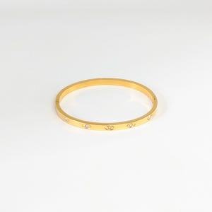 May include: A gold bangle bracelet with small clear stones set into the band.