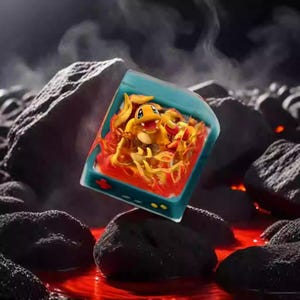 May include: A teal-colored, handheld gaming device featuring a cartoon Charmander character engulfed in flames. The device is set against a backdrop of dark rocks and a fiery, red liquid, creating a dynamic, fantasy-themed scene.