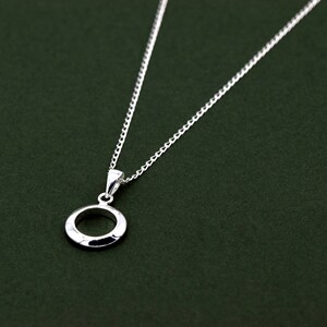 May include: A silver necklace with a simple circle pendant. The pendant has a textured surface.