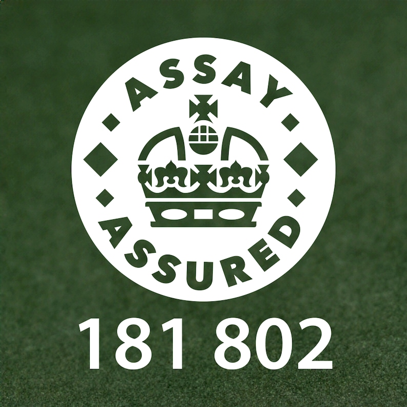 以下が含まれることがあります： 「Assay Assured」というテキストと王冠が描かれた白い円。円の真下に181 802という数字が書かれている。