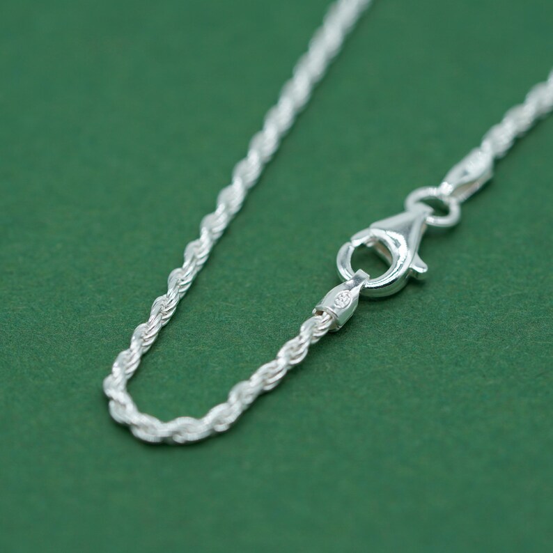 May include: A silver rope chain necklace with a lobster clasp closure.