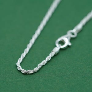 May include: A silver rope chain necklace with a lobster clasp closure.