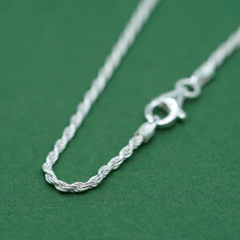 May include: A silver rope chain necklace with a lobster clasp closure.