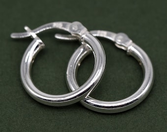 May include: A pair of silver hoop earrings. The earrings are simple and elegant, with a smooth, polished finish.
