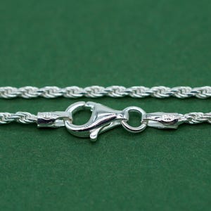 May include: A silver rope chain necklace with a lobster clasp closure.