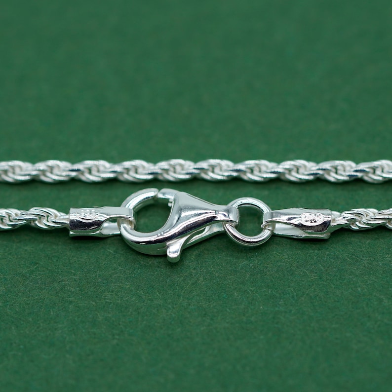 May include: A silver rope chain necklace with a lobster clasp closure.