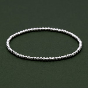 May include: A silver beaded bracelet with a textured finish.