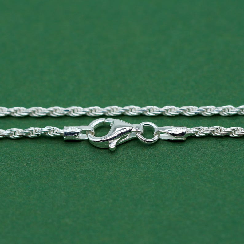 May include: A silver rope chain necklace with a lobster clasp closure.