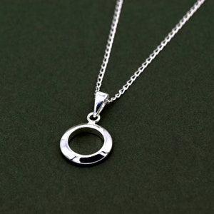 May include: A silver necklace with a simple circle pendant. The pendant has a textured surface and a smooth, polished finish.