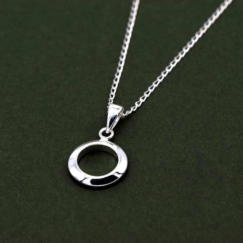 May include: A silver necklace with a simple circle pendant. The pendant has a textured surface and a smooth, polished finish.