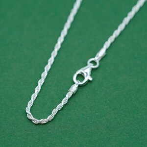 May include: A silver rope chain necklace with a lobster clasp closure.