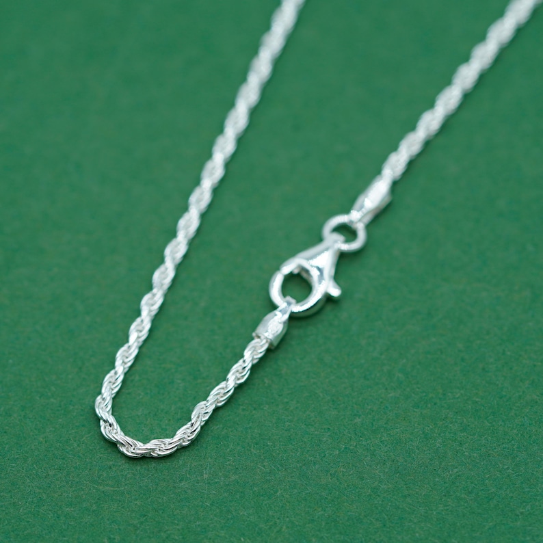 May include: A silver rope chain necklace with a lobster clasp closure.