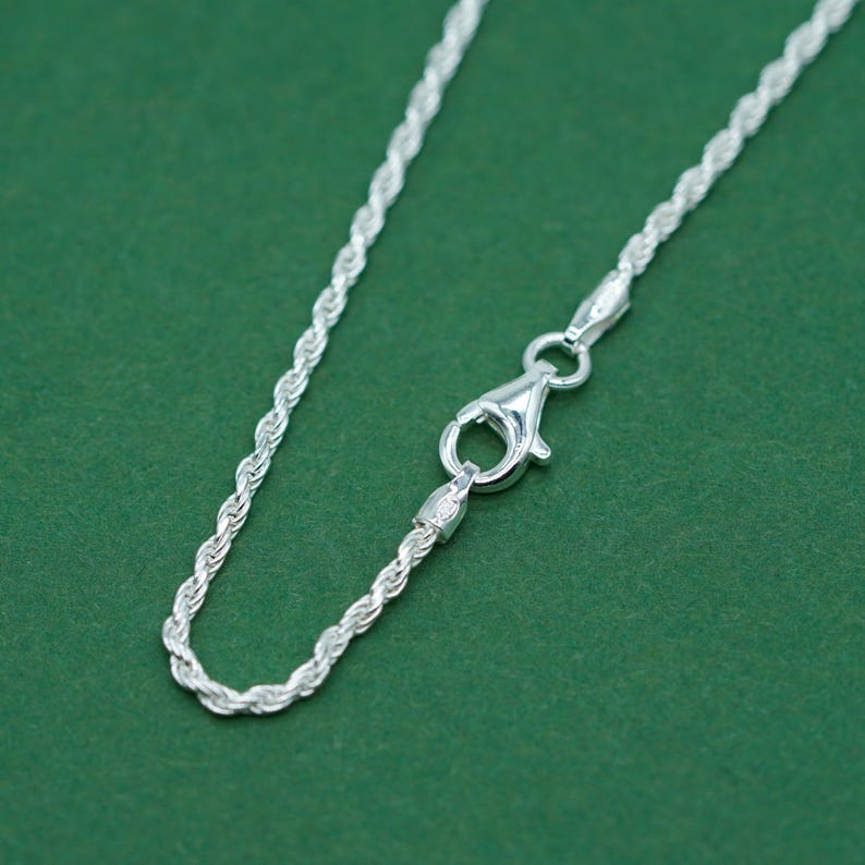 May include: A silver rope chain necklace with a lobster clasp closure.