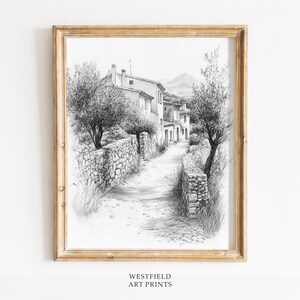 Peut inclure: Tirage d'art encadré en noir et blanc représentant un village européen. L'œuvre présente un chemin de pierre, des murs en pierre, des arbres et des bâtiments. Le cadre est de couleur marron clair. Le texte "WESTFIELD ART PRINTS" est en bas.