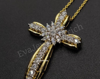 May include: A gold-colored cross pendant necklace with a diamond-studded design. The cross features a central cluster of diamonds and additional diamonds along the arms. The necklace chain is also gold-colored.