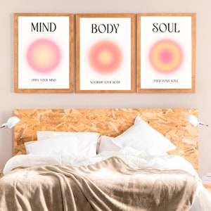 May include: Three framed art prints with the words "MIND", "BODY", and "SOUL" in black text. Each print features a gradient circle in shades of pink and yellow. Below each word is a phrase: "OPEN YOUR MIND", "NOURISH YOUR BODY", and "FEED YOUR SOUL".