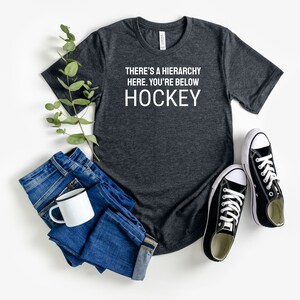 There&#39;s a Hierarchy Here. You&#39;re Below Hockey Shirt Funny Hockey Slogans Tee, Ideal for Game Nights, Great Gift for Hockey Players & Fans