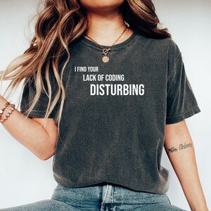 May include: A dark grey t-shirt with the text "I find your lack of coding disturbing" printed in white.