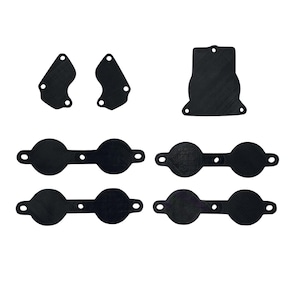 May include: A set of black rubber gaskets for a car engine. The set includes two small, curved gaskets, one large, rectangular gasket, and three pairs of round gaskets.
